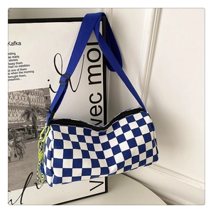 Detail of blue checkerboard canvas bag with blue strap and woven charm accessory