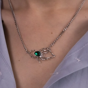 Close-up of gothic silver spider pendant featuring a vibrant oval emerald green stone
