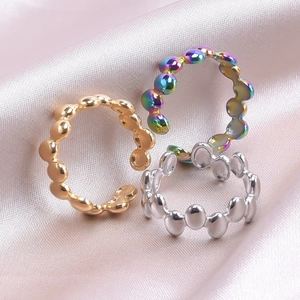 Detailed view of polished beaded rings in gold, silver, and iridescent finishes on satin