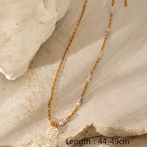 Detail of gold-plated necklace featuring grey marble bead and white tree cutout pendant