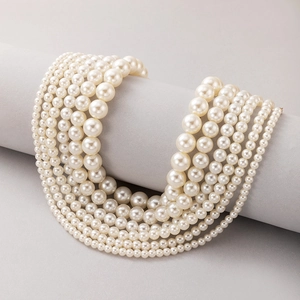 Elegant layered cream white pearl necklaces set on a minimal grey pedestal display