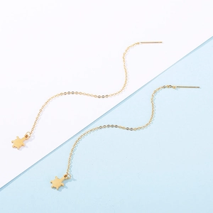 Détail du pendentif tortue dorée sur d'élégantes boucles d'oreilles longues à glands
