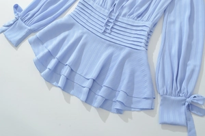 Détail du haut en mousseline bleu clair avec taille smockée, ourlet volanté et nœud