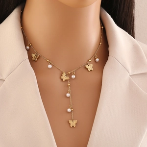 Golden Y-shaped necklace with butterfly charms and pearls on a model wearing a beige blazer