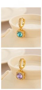 Close-up of square cut zircon earrings in light blue and purple with gold plating