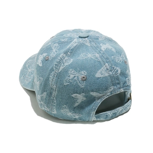 Close-up of white butterfly embroidery on a light blue denim baseball cap detail