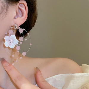 Close-up of floral beaded hoop earrings with pink pearls on model showing detailed texture