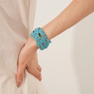 Détail du bracelet multicouche en perles bleu ciel et or sur le poignet