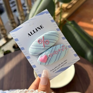 Close-up of blue striped fabric BB hair clips with pink embroidery on display card