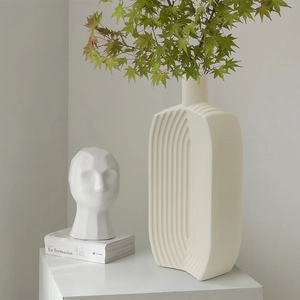 Modern creamy white ceramic vase with vertical ribbed texture and green maple leaves