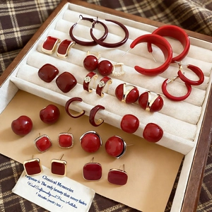 Macro shot of assorted red vintage earrings set inside a cream velvet jewelry box