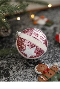 Close-up of pink sequined Christmas ball with star patterns and gingerbread man ornament