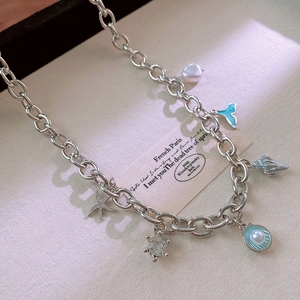 Detailed view of ocean-themed necklace with fishtail, starfish, shell and pearl charms