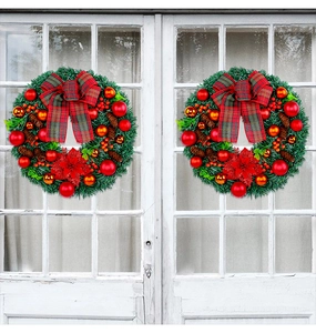 Detailed view of two Christmas wreaths with red bows hanging on white glass doors