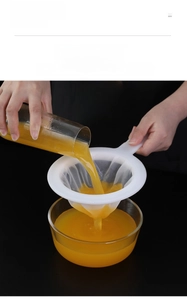 Close-up of fine mesh handheld strainer filtering juice into a glass cup for kitchen use