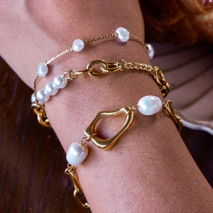 Close-up of three-piece pearl bracelet set with gold metal accents worn on wrist