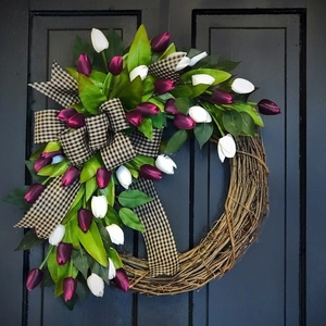 Detailed view of tulip wreath with natural vine base and gingham bow on dark door