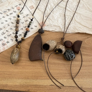 Detail of ethnic pendant necklace with natural wood, stone beads and botanical seeds