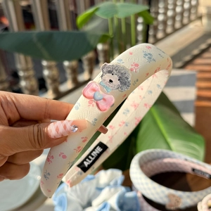 Floral fabric headband with a gray puppy charm and pink bow in an outdoor setting