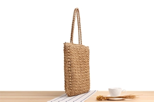 Detailed close-up of handmade woven paper rope tote bag on a rustic wooden table setup