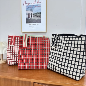 Three minimalist checkerboard knitted tote bags in red, black and white on a wooden counter