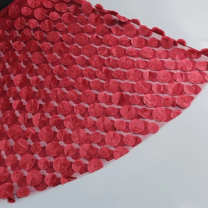 Detailed macro shot of 3D deep red floral applique mesh fabric with intricate stitching