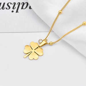 Gold clover necklace with sparkling rhinestone and dainty bead chain on white background