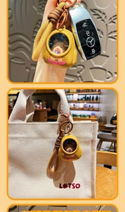 Detail of yellow Capybara keychain with light-up feature hanging on a canvas bag