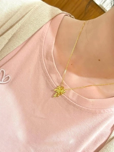 Detailed view of an elegant gold-plated palm leaf necklace worn by a fashion model