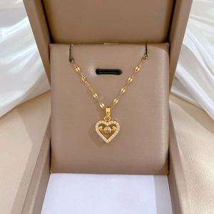 Detail of a gold heart pendant with crystal inlay resting in a beige jewelry box