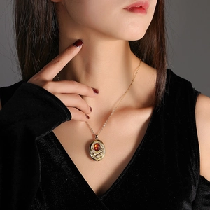 Dettaglio della collana vintage in oro con ciondolo ambra e rilievo floreale su modella