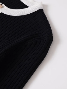 Close-up of contrast knit jacket with black ribbed fabric and golden metal button