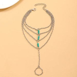 Silver finger bracelet with layered chains and turquoise beads on orange background