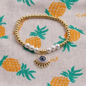 Beaded Evil Eye bracelet with gold copper beads, pearls and blue eye pendant on burlap