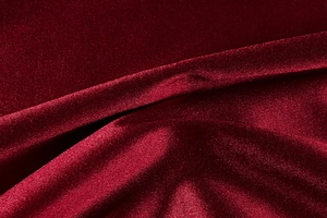 Close-up of premium deep red satin fabric with elegant drapes and silky glossy texture