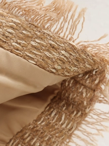 Detaillierte Makroaufnahme einer beigen Tweedjacke mit glänzenden Fäden und Fransen