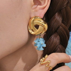 Golden geometric tassel earrings with blue beads and matching ring on model profile