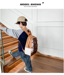 Zijaanzicht van een jongen met bruin-witte schoolrugzak op een trap, ergonomische banden