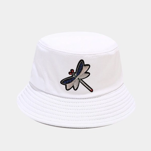 Detailed view of dragonfly embroidery on a white canvas bucket hat with high density texture