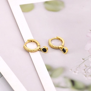 Close-up of gold-plated hoop earrings with black round pendants and micro-set zircons
