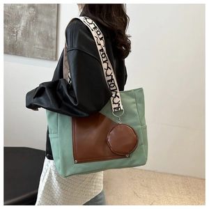 Detail of mint green canvas tote bag with brown leather pocket and patterned strap