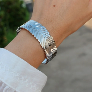 Bracciale rigido aperto a piuma d'argento da donna con trama dettagliata al polso