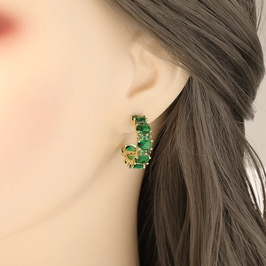 French vintage gold C-shape earrings with emerald green zircons on female model