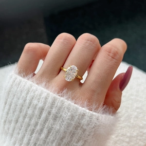Macro shot of an oval cut birthstone ring with golden plating on a finger