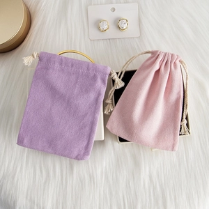 Detailed view of velvet drawstring jewelry pouches with pearl earrings on a plush background