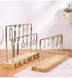 Macro detail of gold metal earring display stand with natural wooden base and jewelry