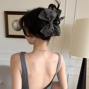 Detailed back view of a grey fabric bow hair claw clip styled on a model's wavy hair