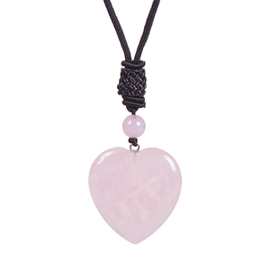 Macro detail of heart-shaped rose quartz pendant with smooth texture and woven black cord