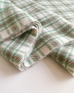 Detailed close-up of green and brown plaid scarf showing soft cashmere-like twill texture