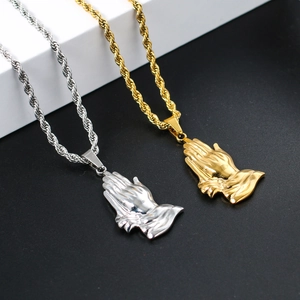 Detailed close-up of gold and silver praying hands pendants with twisted rope chains